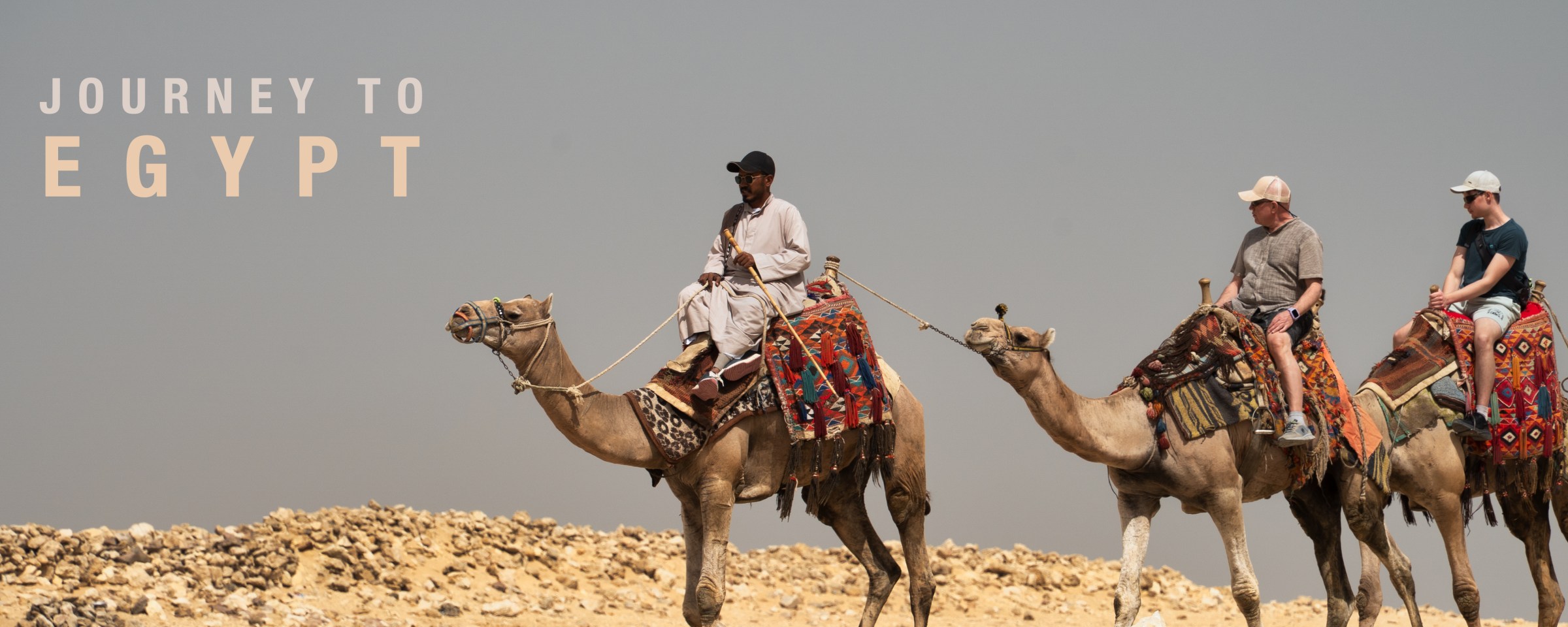 Three camel riders crossing rocky ground beneath the title Journey to Egypt.