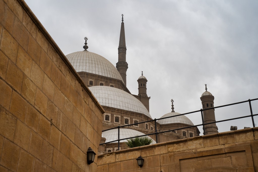 Mosque domes and slender minarets rising above a stone wall.