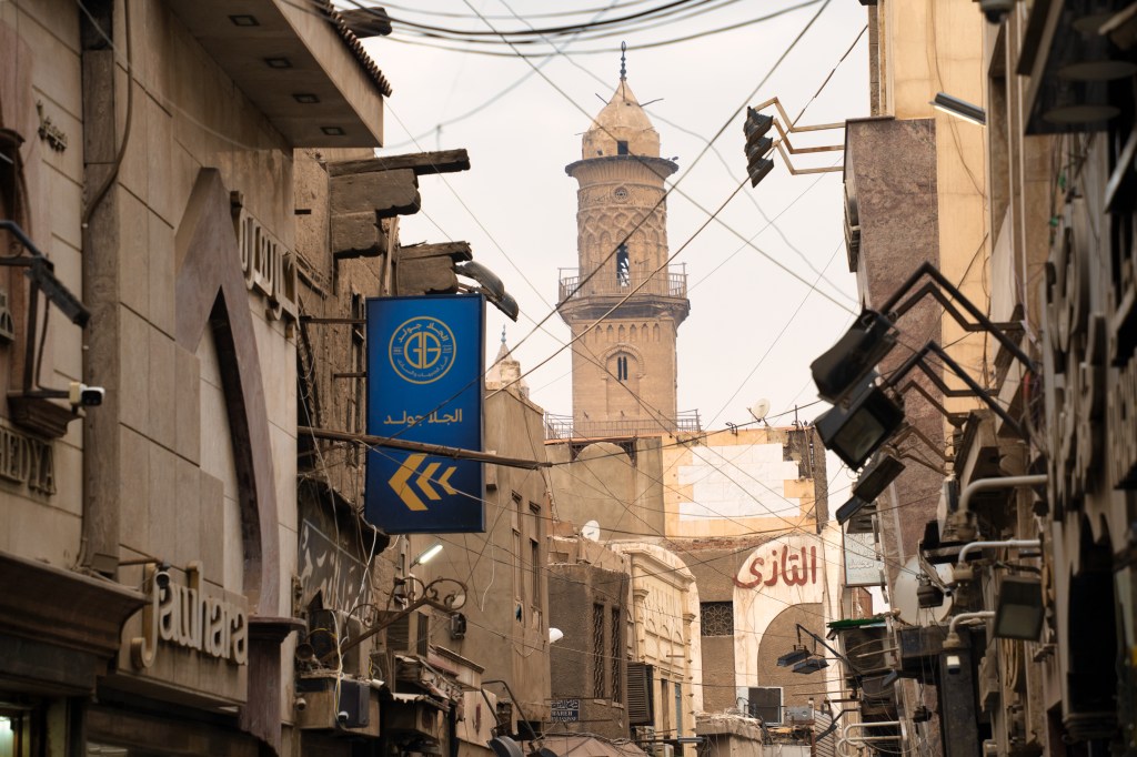A minaret at the end of a narrow Cairo street crossed by overhead wires.