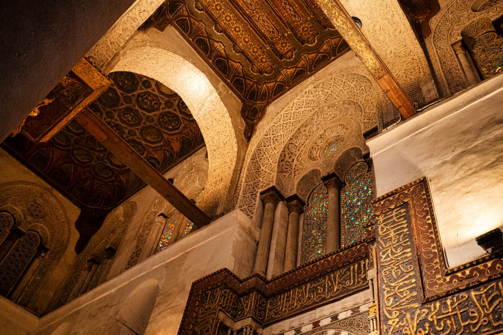 Decorated arches and Arabic inscriptions inside a mosque.
