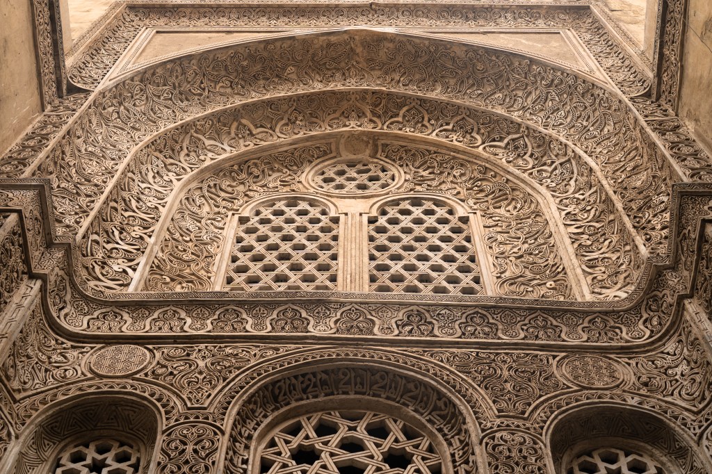Intricate carved stone patterns surrounding arched windows.