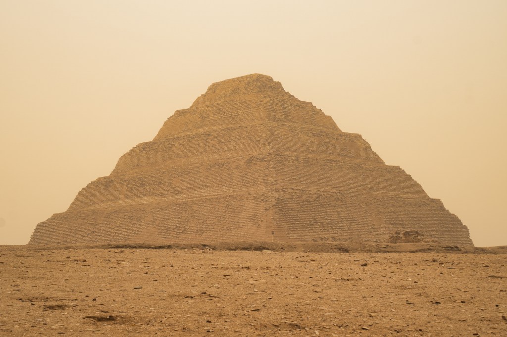 Frontal view of the Step Pyramid and its broad terraces in warm desert haze.